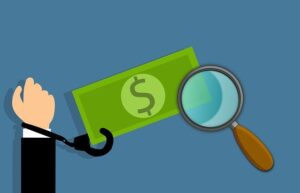 A hand in a suit, cuffed at the wrist, reaches toward a green dollar bill while a magnifying glass examines the money on a blue background, symbolizing financial investigation and crime.
